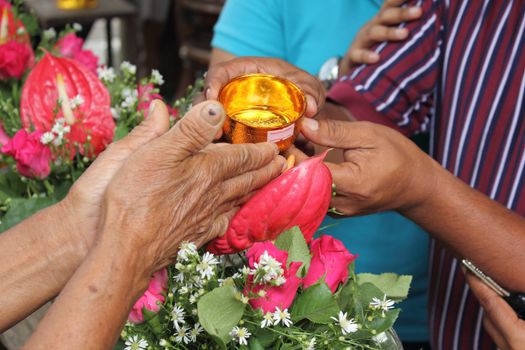 Pour water on the hands of revered elders and ask for blessing in Songkran festival tradition of thailand