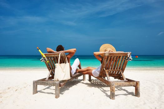 Couple in white relax on a tropical beach at Maldives