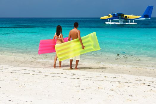 Couple with inflatable rafts looking at arrived seaplane on a tropical beach at Maldives. No brand names or copyright objects