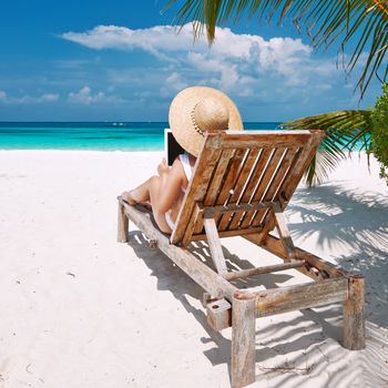 Young woman in hat with tablet pc at the beach