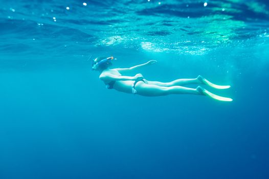 Woman with mask snorkeling in clear water 