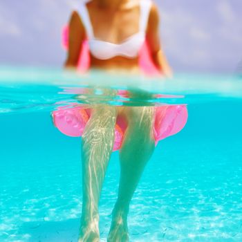 Woman relaxing on inflatable mattress at the beach, view from underwater