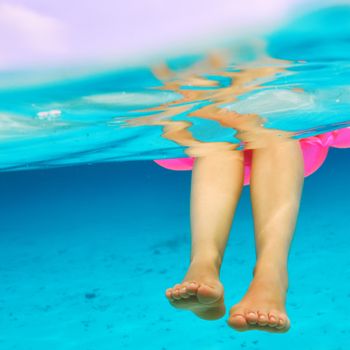 Woman relaxing on inflatable mattress at the beach, view from underwater