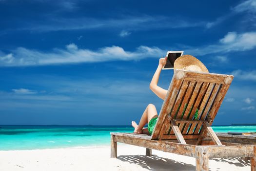 Young woman in hat with tablet pc at the beach