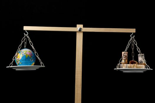 Globe Planet Earth and Money on a Two Pan Balance