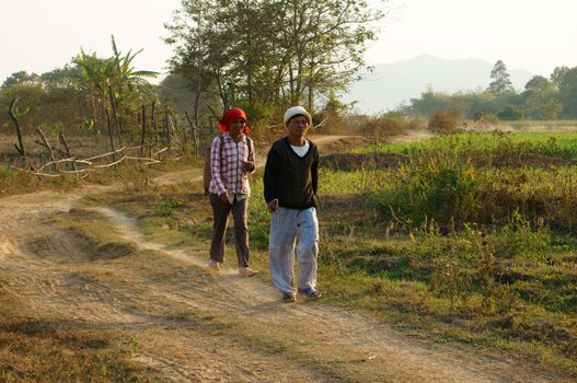 DAKLAK, VIETNAM- FEB 7: Couple of farmer walking on path at countryside to coming home, they walk on dust track in evening make calm view, Viet Nam, Feb 7, 2014