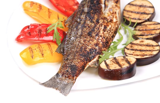 Grilled seabass with vegetables on plate. Whole background.
