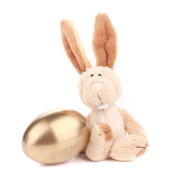 White toy rabbit with golden egg. Isolated on a white background.