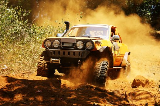 Racer at terrain racing car competition, the car try to cross extreme off road with red earth,  wheel make splash of soil and dusty air, competitor  adventure in championship spirit 