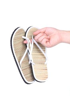 Pair of striped flip-flop sandals in hand. Isolated on a white background
