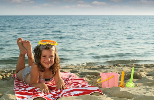 happy little girl lying on beach summer season