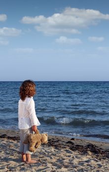 little girl with teddy bear on beach summer season