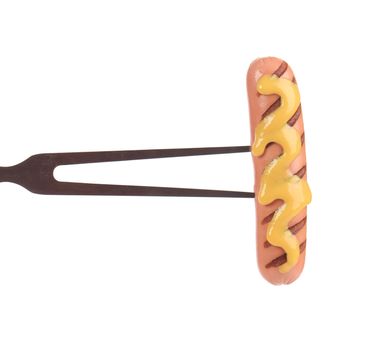 Fried sausage with mustard on a bbq fork