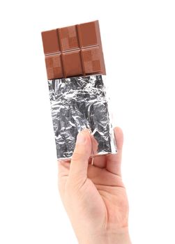 Hand holds dark chocolate bar in foil. Isolated on a white background