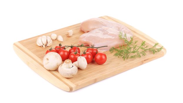 Raw chicken breast and vegetables on the wooden board. isolated on a white background
