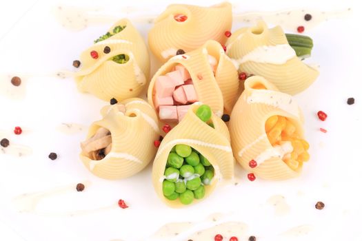 pasta shells stuffed with vegetables and sausage on a white plate.