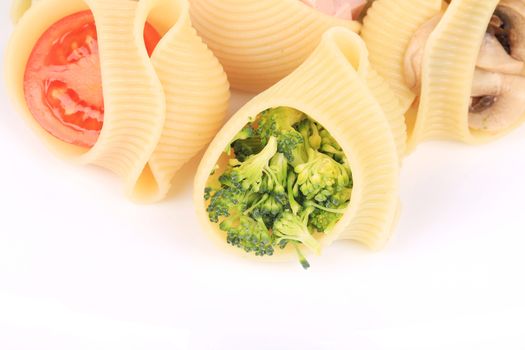pasta shells stuffed with vegetables and sausage on a white plate.