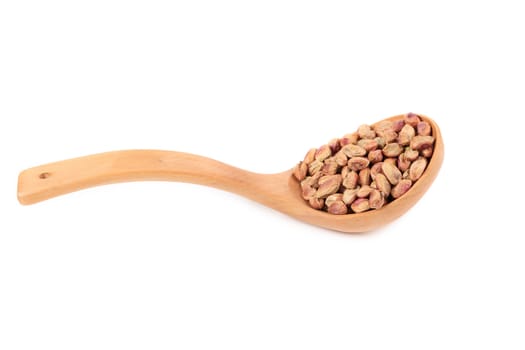 Wooden spoon with pistachios. Isolated on a white background.