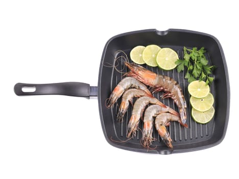 Fresh shrimps on frying pan with lemon slices. Isolated on a white background.