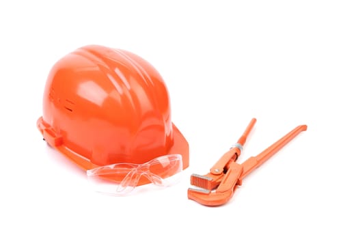 Red safety helmet and adjustable pipe wrench. Isolated on a white background.