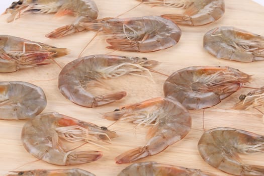 Raw shrimps on wooden board close-up.