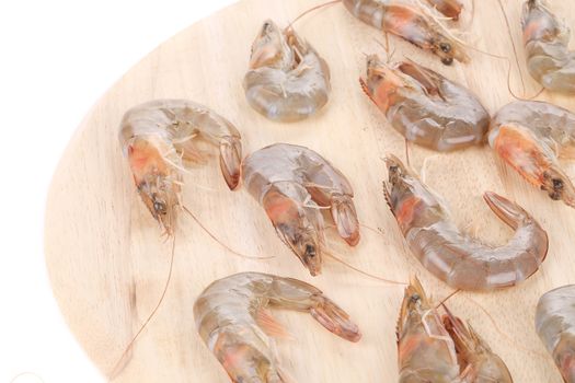 Raw shrimps on wooden round board. Isolated on a white background.