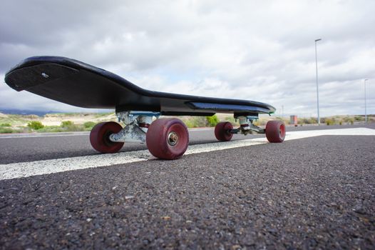 Vintage Style Longboard Black Skateboard on an Empty Asphalt Desert Road