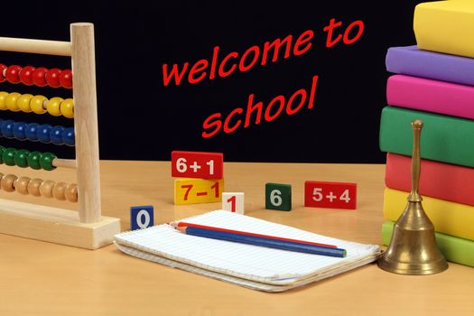 welcome back  to school concept. abacus, bell and books on blackboard