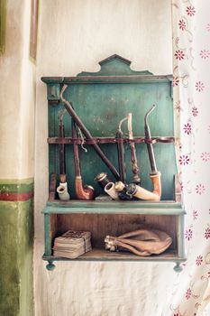 Wooden shelf with a collection of old tobacco pipes