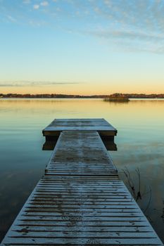 Scandinavian lake in the sunset with a long frozen  jetty