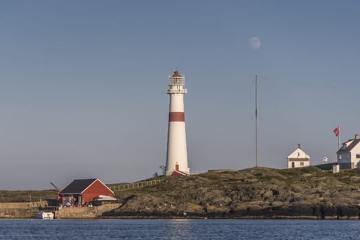 Torungen Lighthouse outside Arendal, Norway. There is a full moon and a clear blue sky.