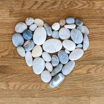 Stones arranged as a heart on a wooden background.