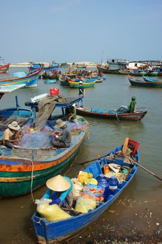 BINH THUAN, VIETNAM- JAN 20: Transportation people and goods by small wooden boat from fishing boat to shore, colorful fishing boat on habor on day at fishing village, Viet Nam, Jan 20, 2014