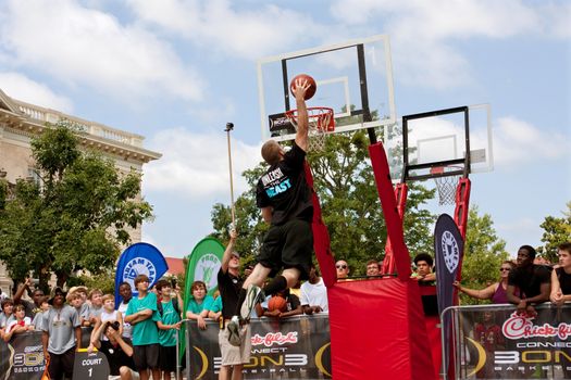 Athens, GA, USA - August 24, 2013:  A young man jumps to dunk the basketball in the slam dunk competition of a 3-on-3 basketball tournament held in the streets of downtown Athens.