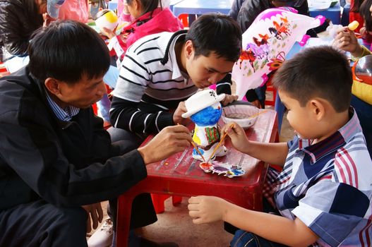 DA LAT, VIETNAM- FEB 1: Man and unidentified boy relax with fun entertainment, they enjoy by paint with water color on plaster figurine, decoration statue with colorful by brush, is trend fun, Vietnam, Feb 1, 2014
