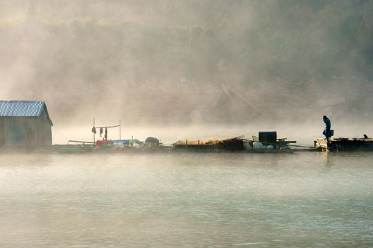 House on lake in foggy morning, vapor from water into air, the man walking on way to home, beautiful landscape of highland