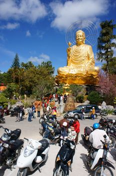 DA LAT, VIETNAM- JAN 31: People go to pagoda to pray lucky, yellow statue of buddha in blue sky, crowd of buddhist visit with belief, faith in buddhism, is traditional culture, viet Nam, Jan 31, 2014
