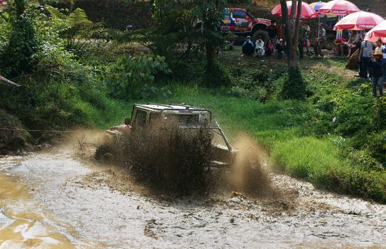 DAMBRI, VIET NAM- FEB 23: Racer offroad at terrain racing car competition, motor wade cross lake, splash mud, competitor  adventure in strong spirit, audience on lakeshore, VietNam, Feb 23, 2014