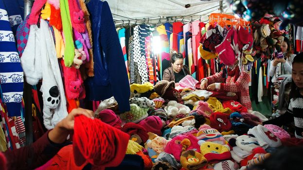 DA LAT, VIET NAM, ASIA- DEC 29: Activity of traveler (tourist) in outdoor market at night, people enjoy and shopping colorful warm clothes as woollen, wooly hat in Dalat, VietNam, Asia, Dec 29, 2013