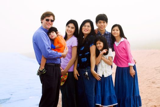 Happy Multiracial family of seven on foggy beach