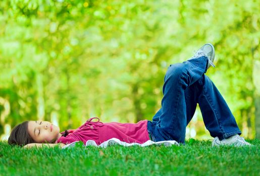 Little girl lying on grass lawn sleeping , one leg crossed over the other