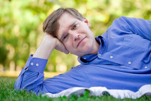 Handsome businessman relaxing on grass in summer