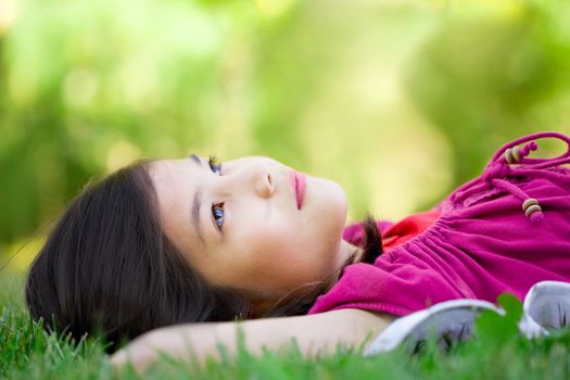 Little girl lying on grass lawn thinking
