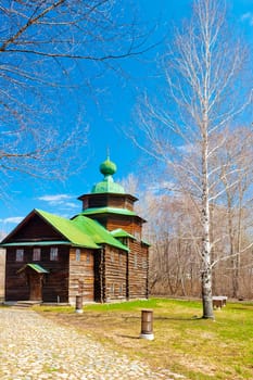 wooden orthodox church with green roof and birch