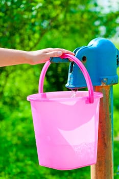 female hand pours water on a column in a bucket