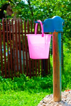 pink plastic bucket and rural well