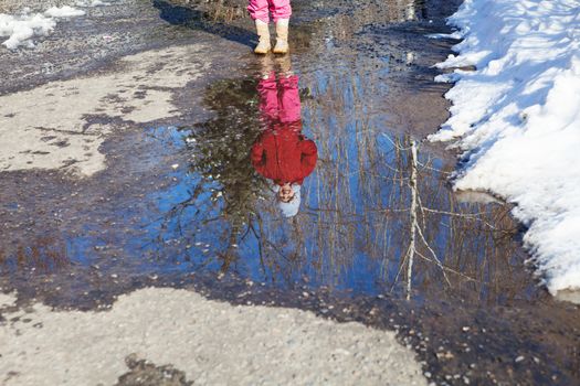 reflection of small girl in spring puddle 