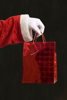 Father Christmas hand holding a red present on blackboard background