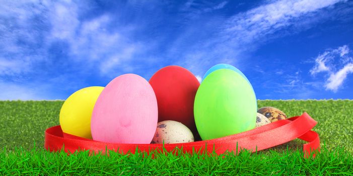 Ester egg on green grass over blue sky background