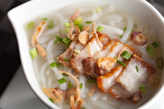 Closeup top down view of Thai style crispy pork rice noodle soup in a bowl. Shallow depth of field.